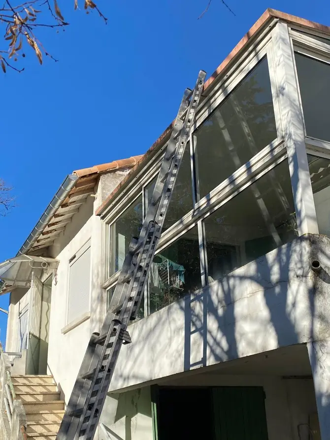 Échelle dressée contre une façade pour accéder à la toiture