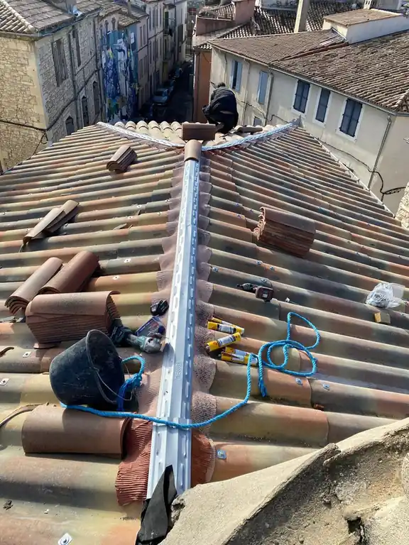 Faîtage en cours de reprise, outils et cordage posés sur le toit