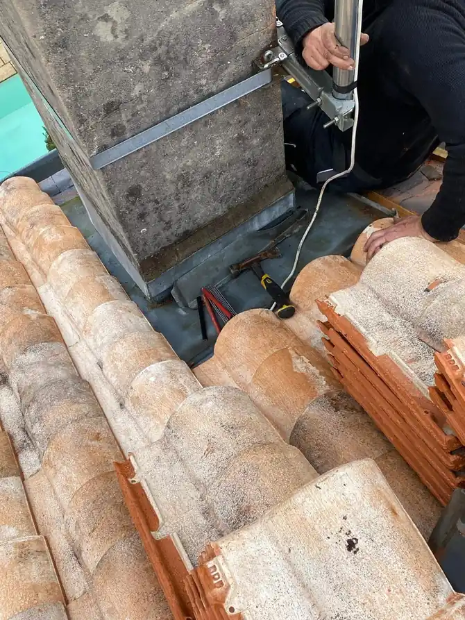 Travail au pied d'une souche de cheminée, tuiles déposées