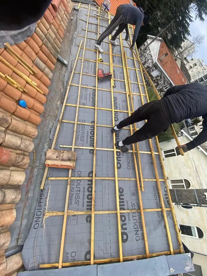 Écran de sous-toiture et liteaux neufs, couvreur au travail